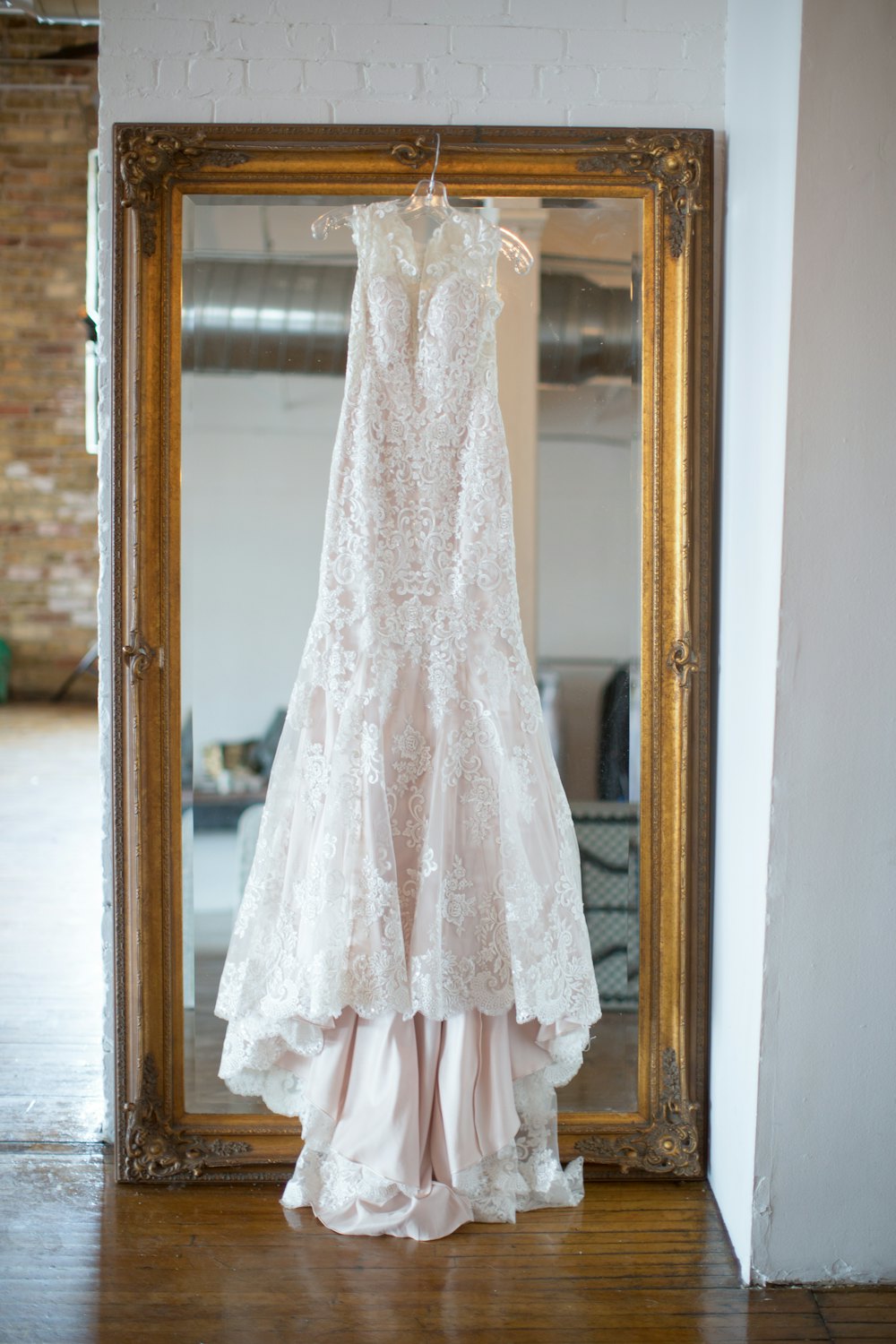 Lace gown hanging in front of a gilt mirror