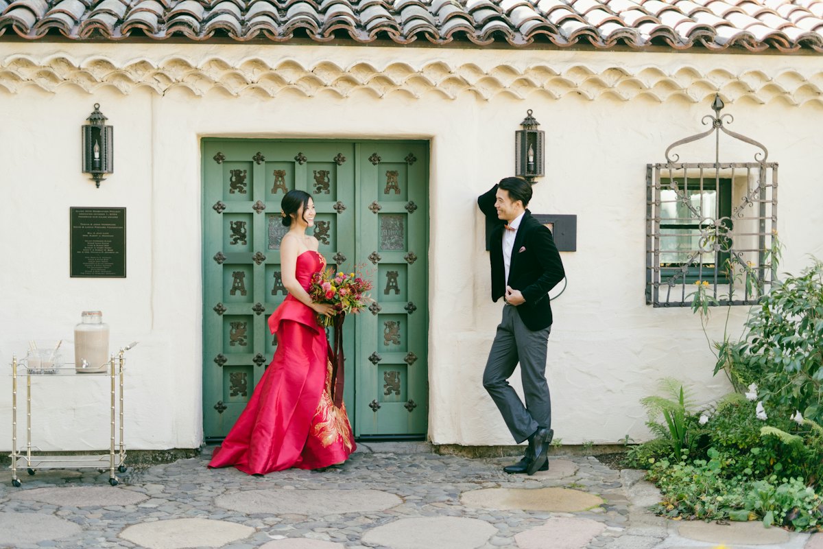 Bride in red outside a white building with a green door