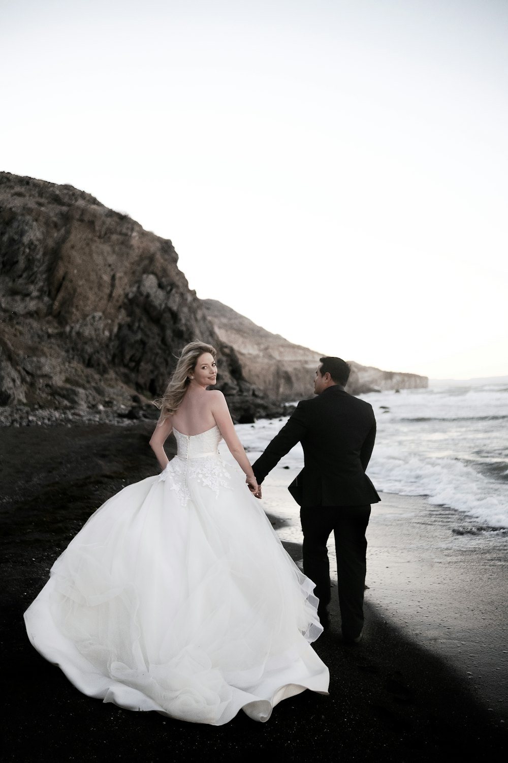 Couple walking along a dark sand beach