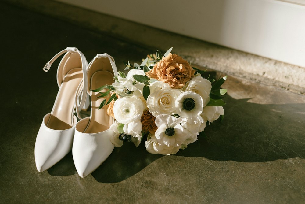 Bridal shoes beside a small bouquet